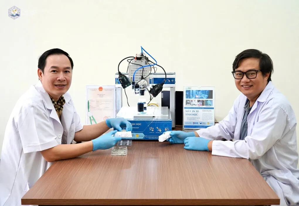 PGS.TS Nguyễn Ngọc Đỉnh (phải), đồng chủ nhiệm và PGS.BS.TS Đỗ Xuân Hai, thành viên chính dự án và hệ máy in 3D sinh học sử dụng mực in tế bào gốc. Ảnh: VNU